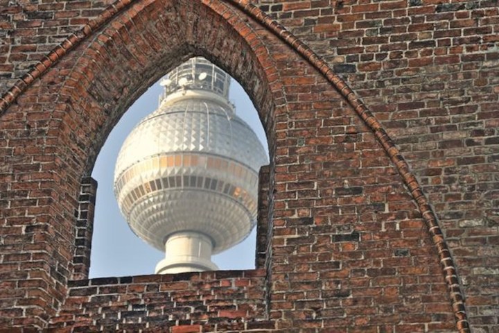 TV tower through arched brick window on a sunny day.