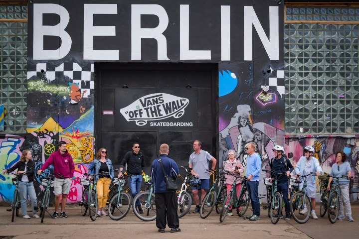 Group of people with bicycles in front of graffiti wall in Berlin.