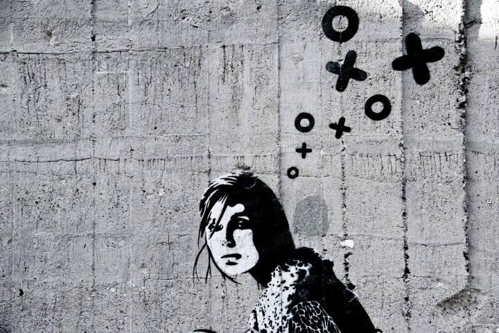 Graffiti of a woman's face on a concrete wall with 'XOXO' bubbles above her head.