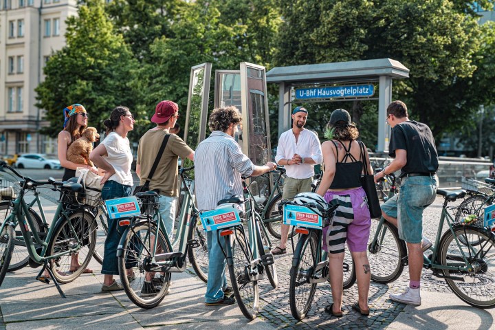 Group of cyclists gathered near U-Bahn station in Berlin, listening to a guide.