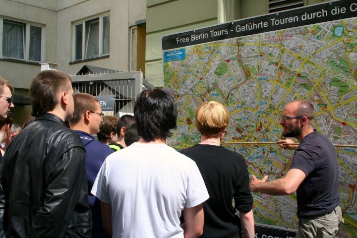 Guide explaining a large city map to a group of people outdoors.