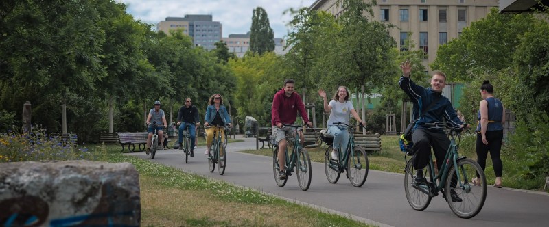 Group of people cycling on a path in an urban park.